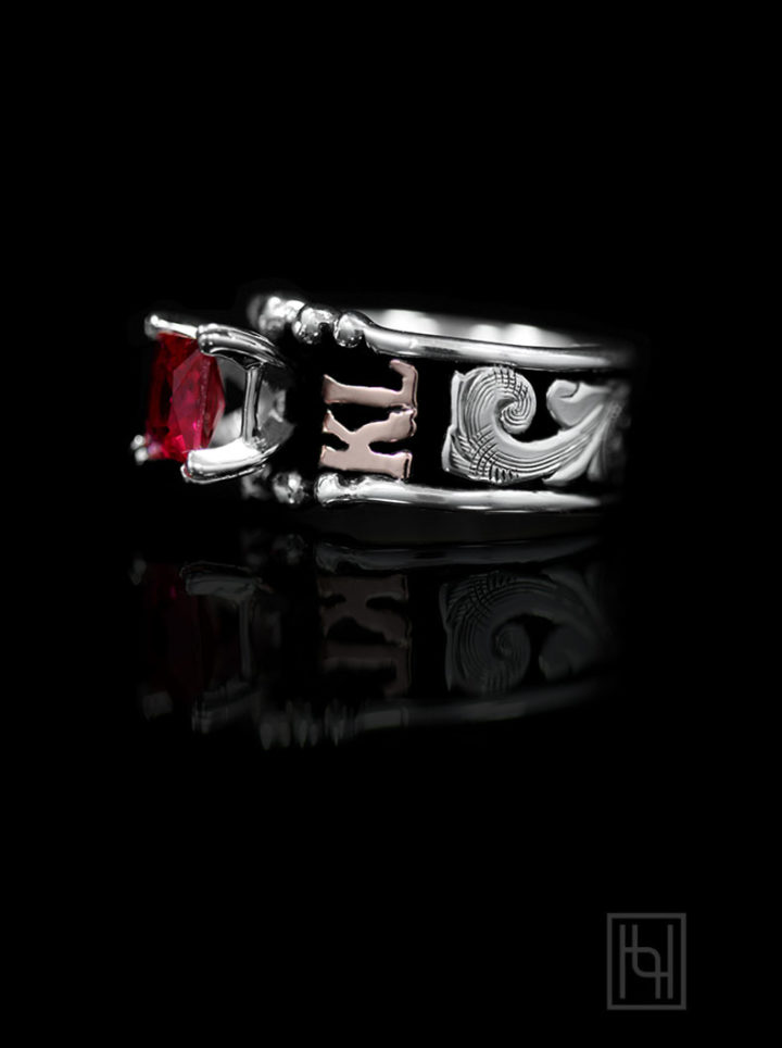 Black background w/ silver scrolls, rose gold lettering, 6mm square ruby red stone on prongs, side view