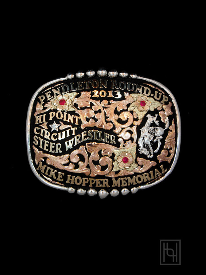 Black background w/ rose gold scrolls, yellow gold lettering, ruby red cz stones, silver casted bucking bronco