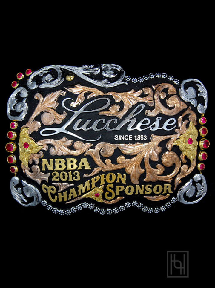 Black background w/ rose gold scrolls, yellow gold lettering and flowers, ruby red cz stones in flowers and edge, Lucchese logo