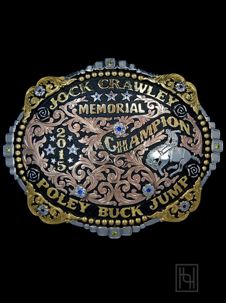 Black background w/ rose gold scrolls, yellow gold edges and lettering, silver bronc rider figure and flowers w/ sapphire blue cz stones