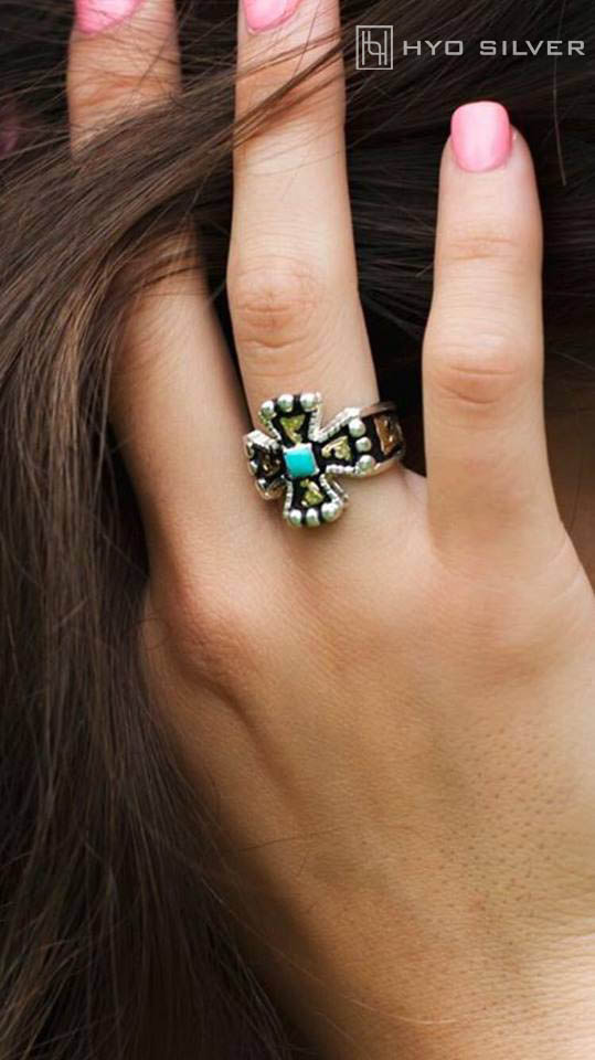 Lifestyle photo of model wearing chopper ring with black background, yellow gold scrolls, blue turquoise stone in center