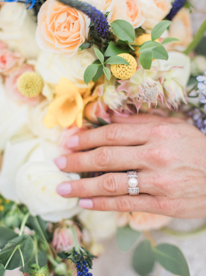 Cathedral Pearl Ring worn on model's hand holding bouquet