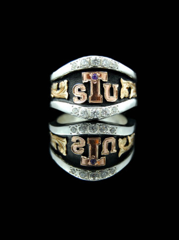 Custom ring w/ black background, yellow gold scrolls, rose gold Tarleton State University logo in center, crystal clear cz stones in edge