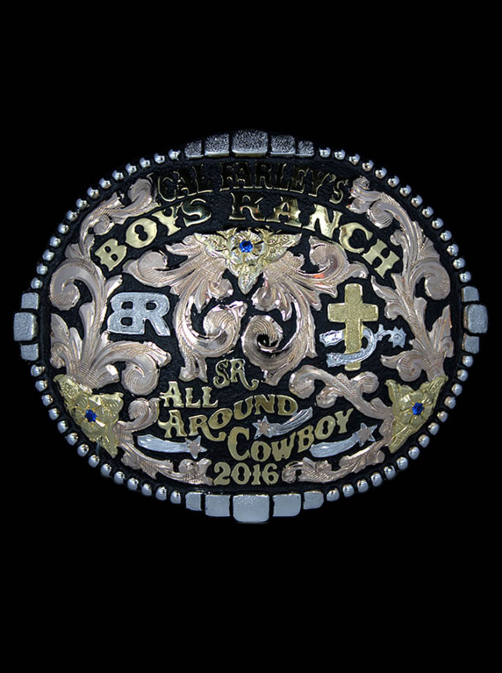 Yuma Custom Buckle with black background, rose gold scrolls, yellow gold flowers and lettering, cross and spur